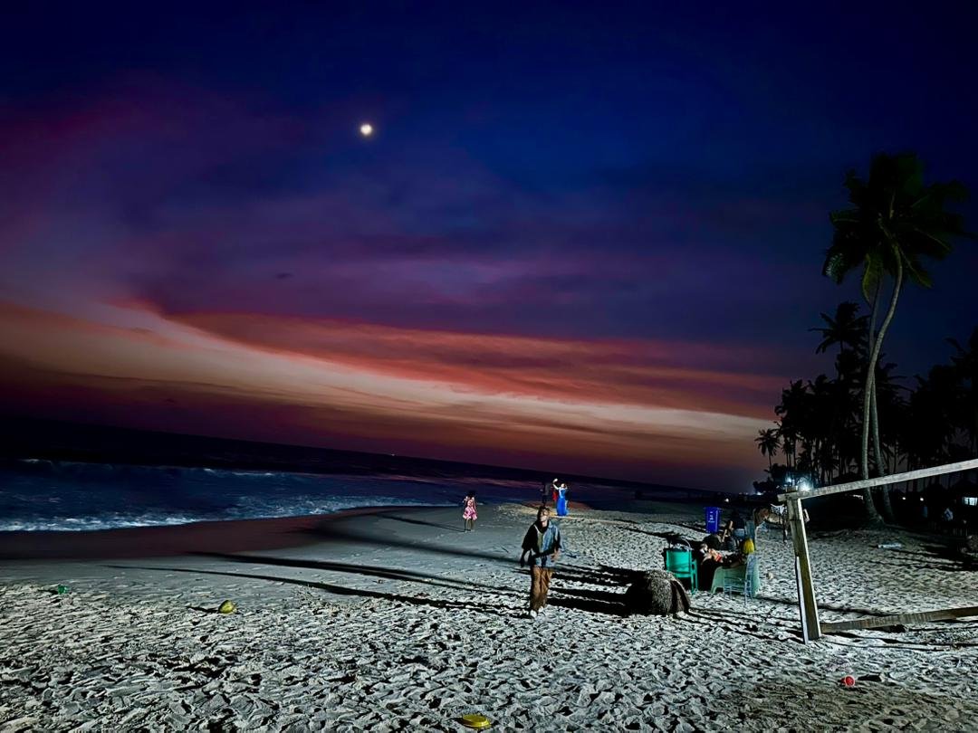 The shoreline at dusk under a pink sky and full moon